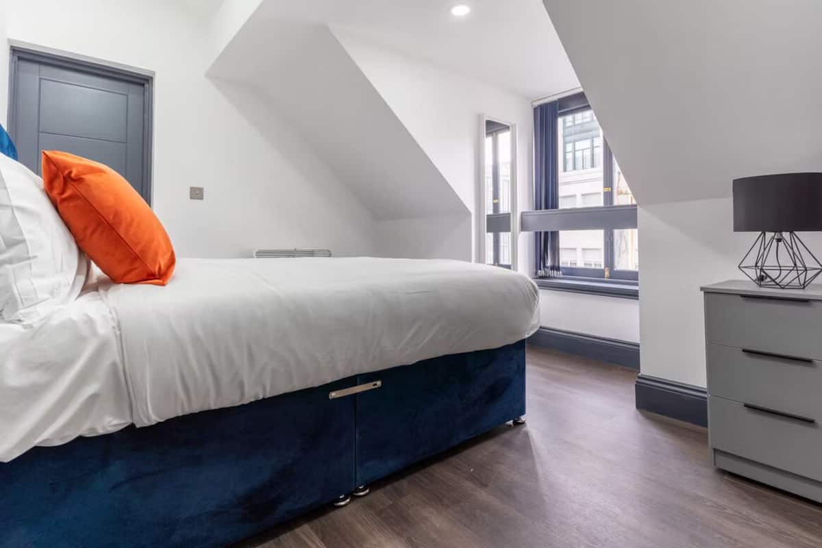 Une chambre à coucher moderne, avec un lit, une commode et une fenêtre.