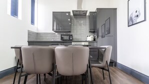 Een moderne keuken met een eethoek, met een centraal kookeiland, grijze kastjes en een magnetron.