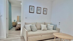 Ein Wohnzimmer mit einem beigen Sofa, einem Holztisch und drei gerahmten Blumenbildern an der Wand.