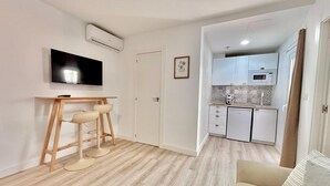 Ein kompakter Wohnraum mit Küchenzeile, einem Essbereich mit Fernseher und einer Couch.