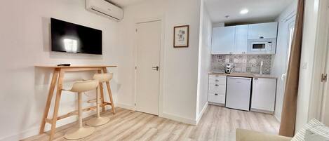 A compact living space with a kitchenette, a dining area with a TV, and a sofa.