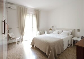 A minimalist bedroom with a large bed, a bedside table, a chair, and a wardrobe. - Centrally located apartment in Garda, 2 bedrooms, 300 m from the lake, parking available (Garda)