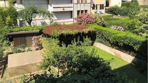 Ein Wohngebiet mit einem Haus, das ein Ziegeldach, einen Garten mit verschiedenen Pflanzen und Blumen sowie einen kleinen Teich hat.