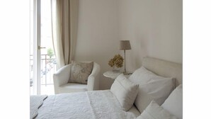 Ein Hotelzimmer mit Bett, Stuhl, Lampe und Blick ins Freie.