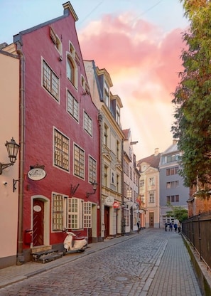 Eine Kopfsteinpflasterstraße gesäumt von historischen Gebäuden, darunter ein rotes Gebäude mit der Aufschrift 'Hotel'.