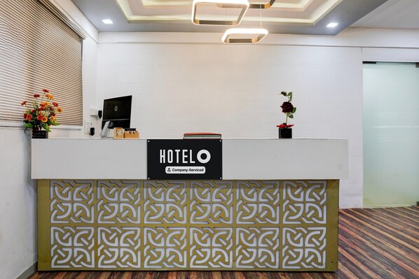 A hotel reception desk with a sign reading "HOTEL O Company-Serviced".