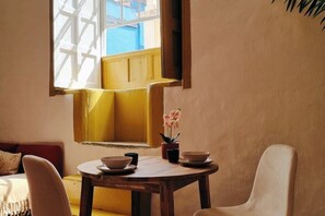 A dining area with a round wooden table, two chairs, and a window with a view of a yellow building. - Suite Ponte - Historic Mansion with Patio & Terrace View (La Orotava)