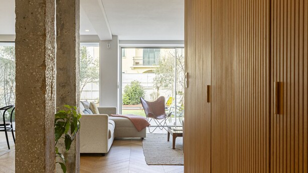 Un interior moderno con piso de espiga, un gran panel de madera en la pared y una zona de estar con sofá y sillones.
