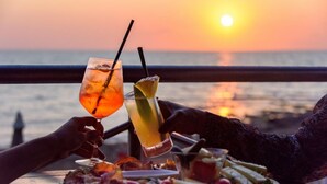 Une vue sur le coucher de soleil, avec une table dressée pour un repas et deux boissons.