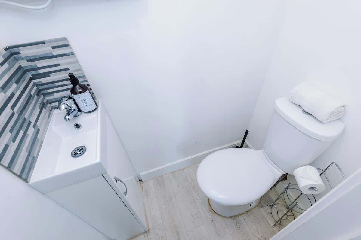 A small, modern bathroom with a white sink, toilet, and a striped tile backsplash.