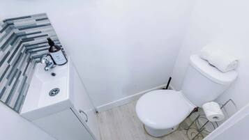 A small, modern bathroom with a white sink, toilet, and a striped tile backsplash.