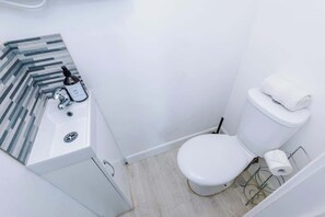 Ein kleines, modernes Badezimmer mit Waschbecken, Toilette und einer Rückwand aus Streifenfliesen.