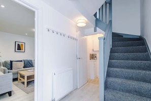 Un intérieur moderne avec un escalier, une porte blanche et un espace de vie comprenant un canapé et une table basse.