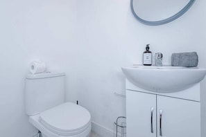 Une salle de bain moderne avec des toilettes, un lavabo surmonté d’un miroir et une serviette posée sur le lavabo.