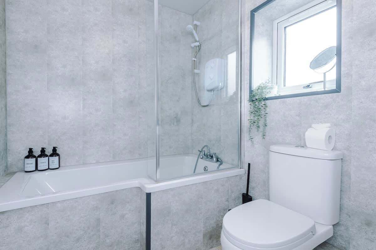 A bathroom with a glass-enclosed shower, a white sink, and a toilet.