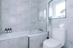 Ein Badezimmer mit Duschkabine, weißem Waschbecken und Toilette.