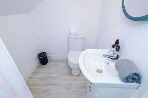 A small bathroom with a toilet, sink, and a trash bin.