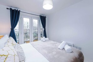 Ein Hotelzimmer mit Bett, Vorhängen, einem Fenster und Blick ins Freie.