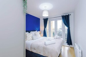 Ein Hotelzimmer mit Bett, einem fenster mit Vorhängen, einer Deckenleuchte und Blick nach draußen.