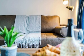 Ein modernes Wohnzimmer mit einer Couch, einer Topfpflanze und einer Lampe.
