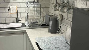 A modern kitchen with a marble backsplash, stainless steel appliances, and a granite countertop. - Wonky 2 A Cosy Hideaway in the Heart of Cheshire (Macclesfield)