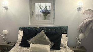A neatly made bed with a patterned bedspread, two bedside tables with decorative lamps, and a framed picture above the bed. - Wonky 2 A Cosy Hideaway in the Heart of Cheshire (Macclesfield)