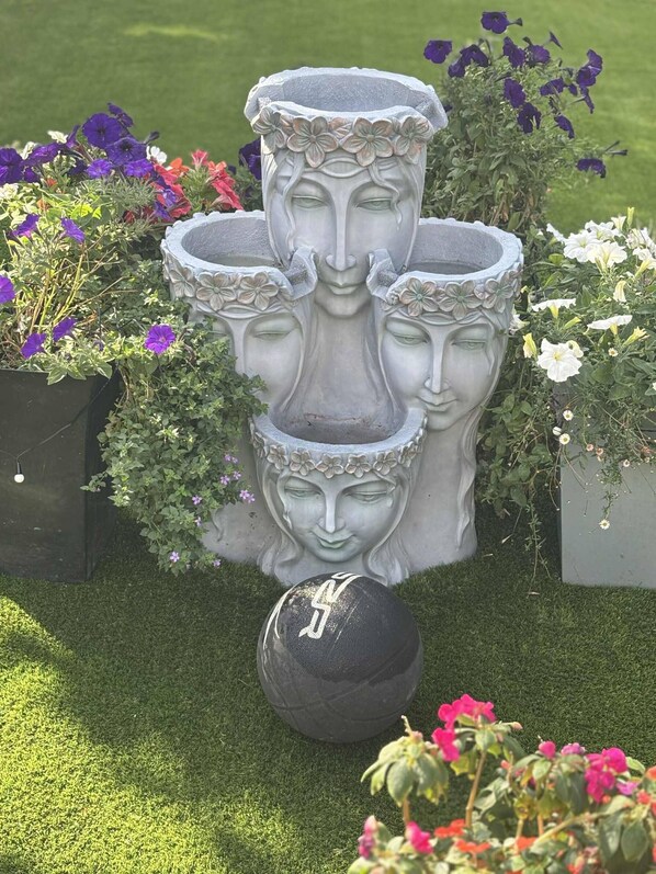 A garden with a central sculpture surrounded by flower beds. - Wonky 2 A Cosy Hideaway in the Heart of Cheshire (Macclesfield)