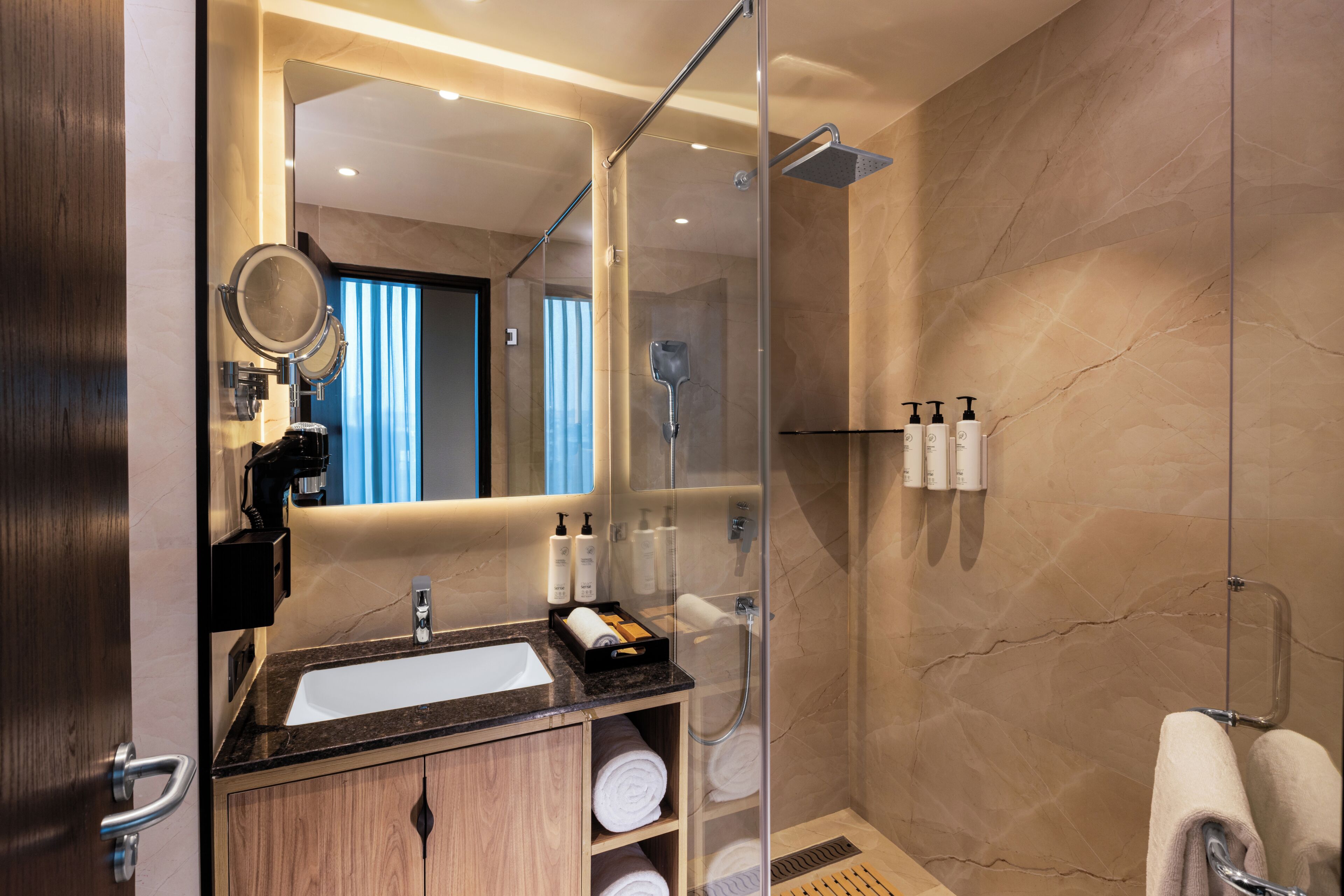 Une salle de bain moderne avec une douche à parois de verre, un lavabo avec un miroir et des serviettes soigneusement rangées.