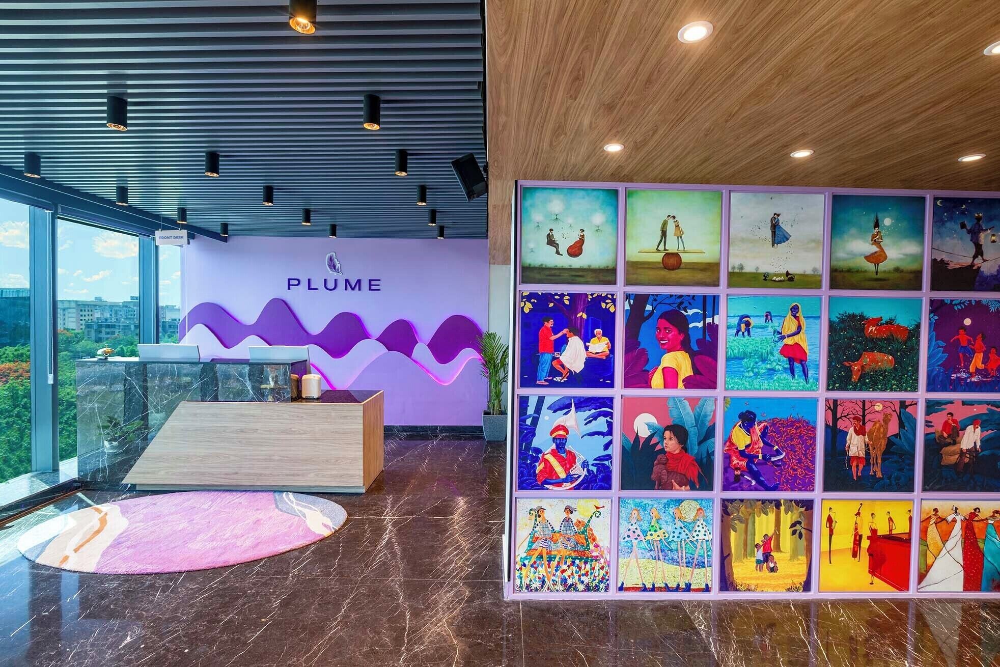 A modern reception area with a marble floor, a wooden reception desk, and a large wall of colorful artwork.