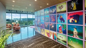 Un interior moderno con un ventanal grande, una mesa de vidrio y una pared llena de obras de arte coloridas.