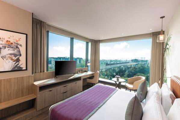 Una habitación de hotel moderna con una cama grande, un escritorio, un televisor y vistas a la ciudad.