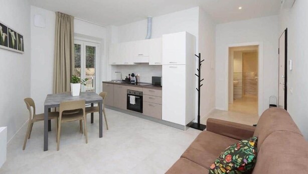 Um apartamento moderno com área de refeições, pequeno espaço de cozinha e sala de estar com sofá.