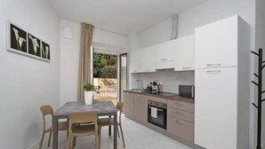 Uma cozinha compacta com área de refeições, uma janela com cortinas e um vaso de planta.
