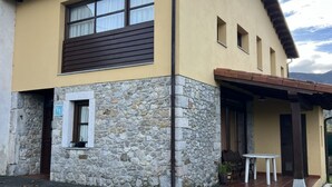 A building with a stone facade, a brown window, and a small porch with a table and chairs. - House for 8 Bufones de Pría (Pria)