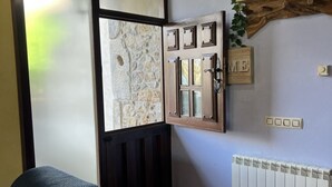 A room with a stone wall, a wooden door with glass panels, a radiator, and a wall-mounted light switch. - House for 8 Bufones de Pría (Pria)