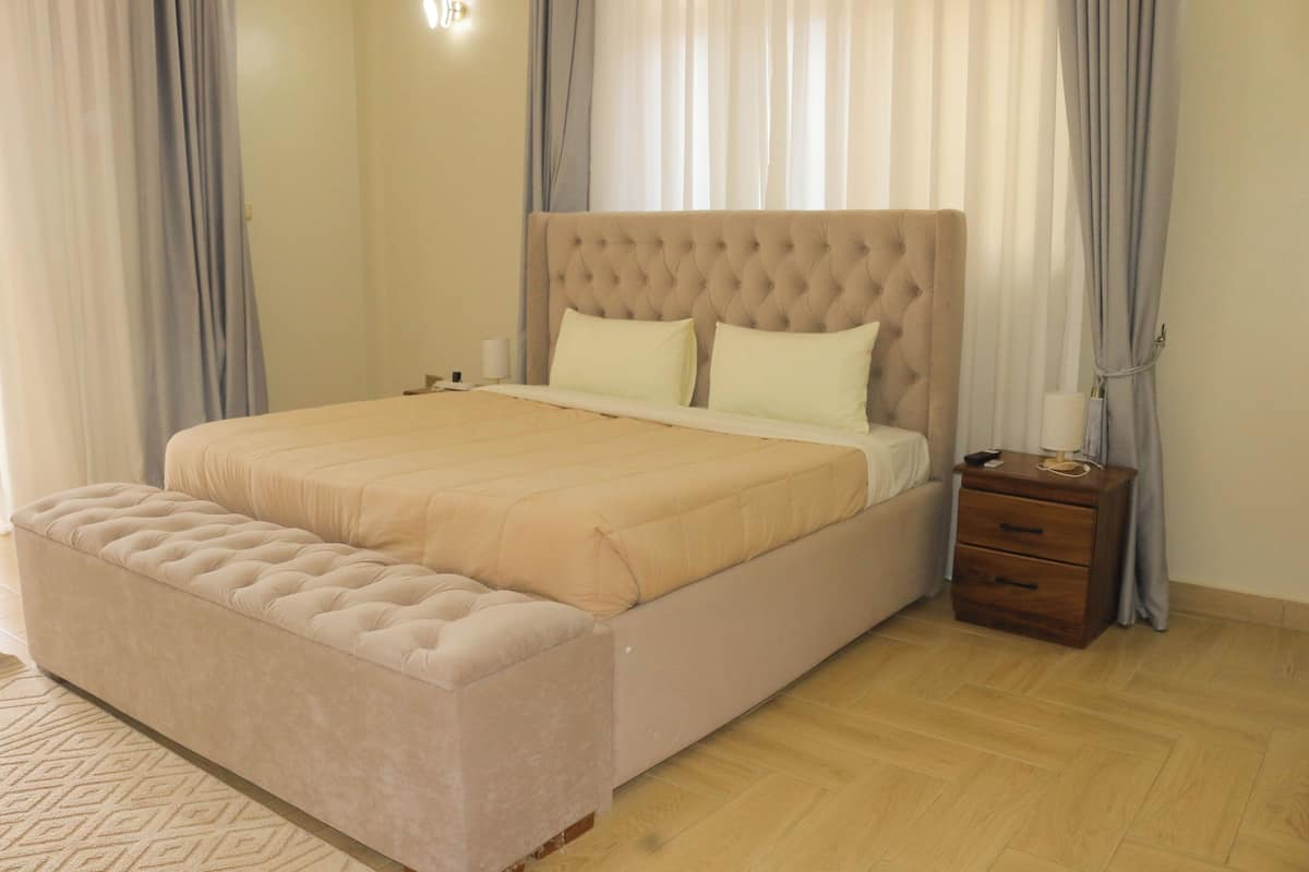 Un dormitorio con una cama grande, una mesita de noche y suelo de madera.