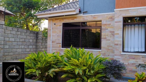 A residential building with a stone facade, a tiled roof, and a window with a curtain. - Residence Six Sigma (Entebbe)