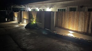 Un edificio moderno con fachada de hormigón, paneles de madera en las paredes y varias luminarias.