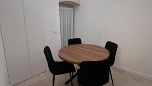 Una habitación pequeña con una mesa redonda de madera y cuatro sillas negras.