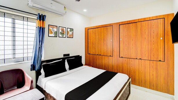A bedroom with a bed, a ceiling fan, an air conditioning unit, a window with curtains, and a wooden wardrobe. - Hotel O Snist University Hyderabad (Hyderabad)