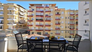 A balcony with a table set for breakfast, overlooking a multi-story residential building. - Holiday Apartment In Saranda - 003 With Balcony (Sarandë)