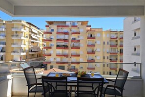 En balkon med et bord dækket til morgenmad, med udsigt over en høj bygning.