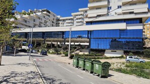 A multi-story residential building with balconies, a pedestrian crossing, and parked cars. - Holiday Apartment In Saranda - 003 With Balcony (Sarandë)