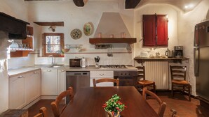 Una cocina con armarios blancos, una mesa de comedor de madera y un armario rojo.