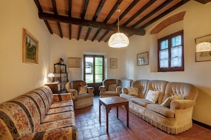 A cozy living room with a wooden ceiling, a sofa set, a coffee table, and a window with curtains.