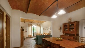 Un coin repas comprenant une table et des chaises en bois, un canapé et un meuble avec des portes en verre.