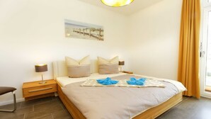 A bedroom with a large bed, two bedside tables, a nightstand, and a painting on the wall. - Large apartment in Karlshagen on Usedom with sauna, close to the beach (Karlshagen)