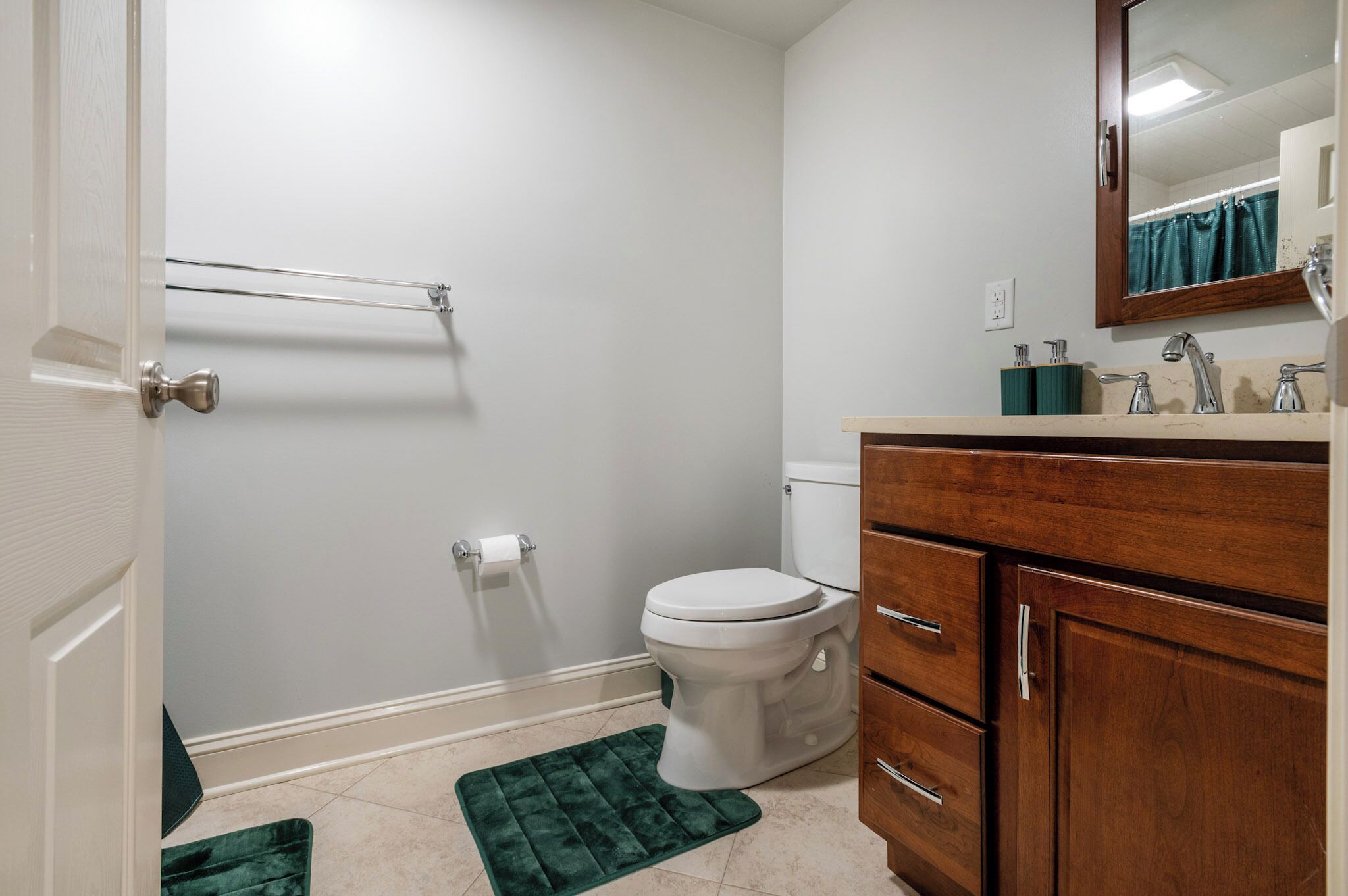 Un baño con inodoro, tocador de madera, espejo y zona de ducha.