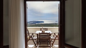 A balcony with a table and chairs, overlooking a coastal landscape with mountains and a body of water. - Apartment - Sleeps 4 - Parking - Sea View (Pyrgos)