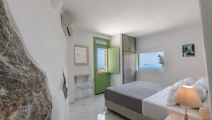 A bedroom with a bed, a desk, a chair, a window with a view, and a wall with a picture. - Apartment - Sleeps 4 - Parking - Sea View (Pyrgos)